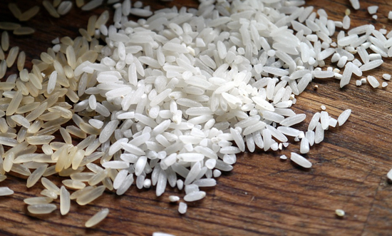 Brown and white rice grains on rustic wood, highlighting textures and culinary contrasts.