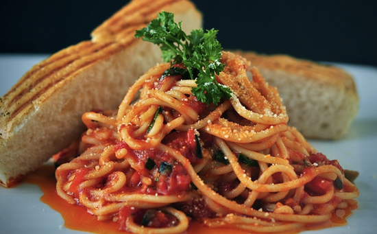 Delicious spaghetti with tomato sauce and grilled bread, garnished with parsley and cheese.