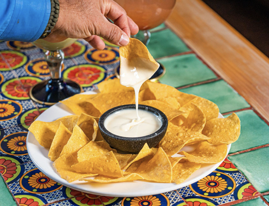Delicious nachos with cheese dip, perfect for sharing at gatherings or casual dining experiences.