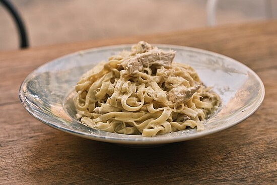 Delicious fettuccine Alfredo with chicken served in a rustic bowl on a wooden table.