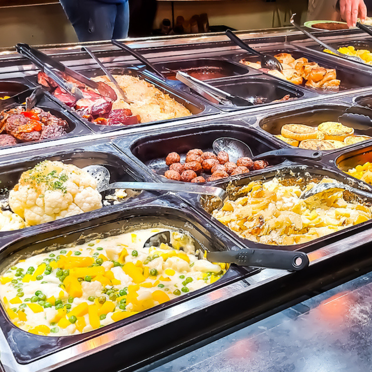Vibrant buffet display featuring diverse dishes, including creamy vegetables and savory meats.