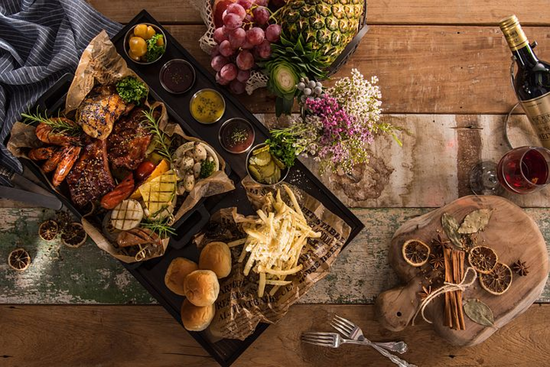 Grilled meats, French fries, and fresh fruits create a vibrant, rustic dining experience.