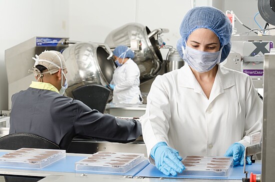 Workers in a sterile laboratory ensuring food safety and quality through careful handling processes.