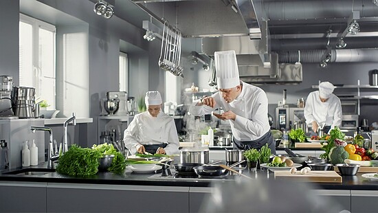Professional chefs prepare vibrant dishes in a modern, bustling kitchen filled with fresh ingredients.