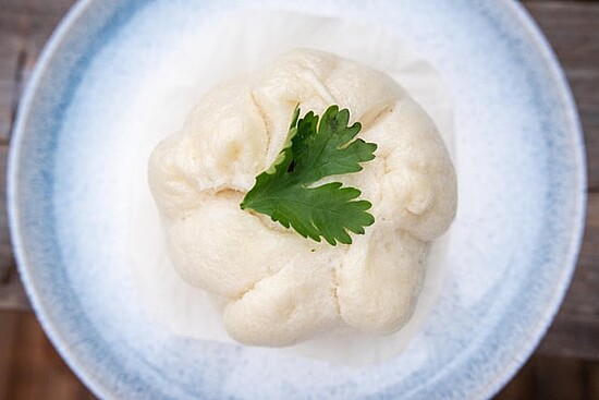 Delicious steamed bao with cilantro on a rustic plate, evoking comfort and culinary tradition.