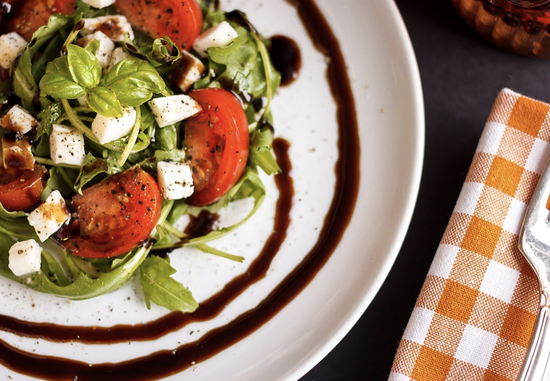 Vibrant salad with arugula, tomatoes, cheese, and balsamic reduction for a fresh, flavorful meal.