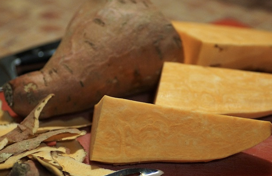 Vibrant sweet potatoes and fresh slices showcased on a rustic cutting board.