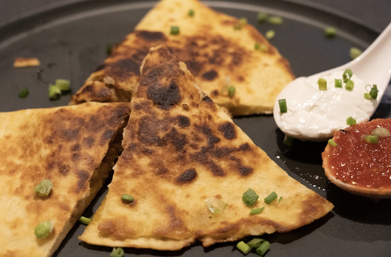 Crispy quesadillas with dipping sauces on a stylish black plate at Chairmans Tacobar.