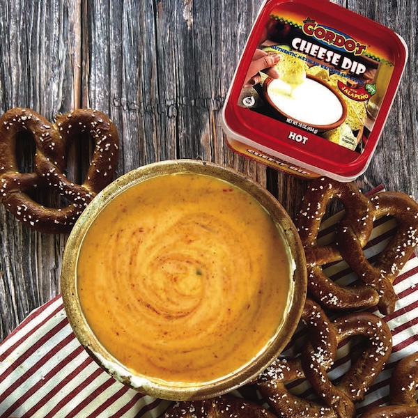 Condor hot cheese dip in serving bowl alongside fresh pretzels and branded packaging, ideal for foodservice and wholesale distribution.