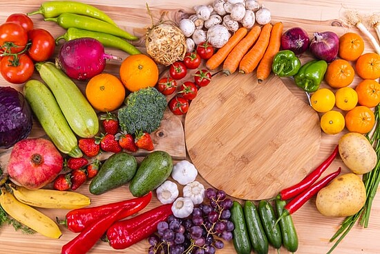 Vibrant assortment of fresh fruits and vegetables on a wooden cutting board.